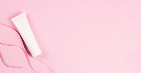 Concept beauty, self care, treatment. Cream tube and paper wave on pink background, flatlay, banner, copyspace.の写真素材