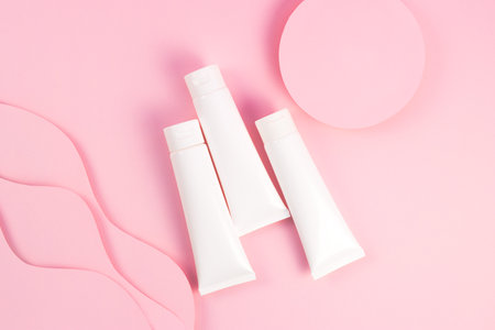 Concept beauty, self care, treatment. Set with cream tube and paper sun waves on pink background, flatlayの写真素材