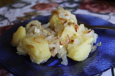 boiled potatoes with fried onions on a blue plate, home-made foodの写真素材