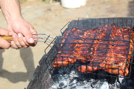 a man holds a grill with a freshly cooked grilled barbecueの写真素材
