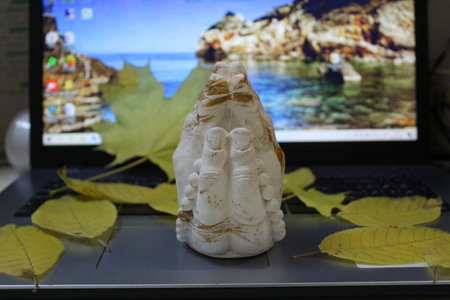 hands in prayer close-up and laptop with autumn leavesの写真素材