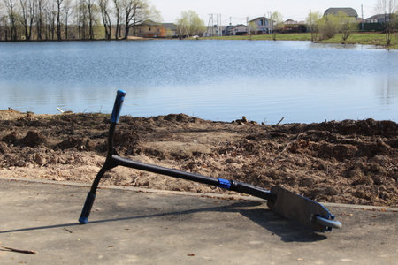 a close-up of a children's scooter lies on the shore of a lakeの写真素材