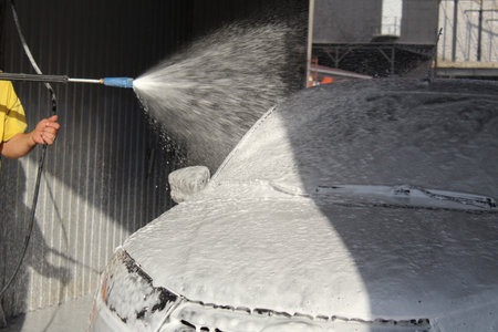 a black car is washed with foam at a car washの写真素材