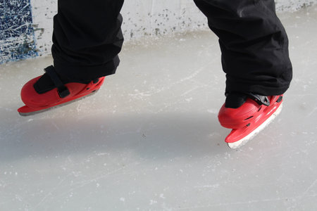 feet in red skates on an ice rink, closeup of photoの写真素材