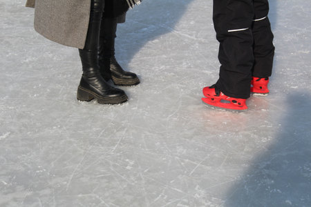 legs of a woman and child skating in winterの写真素材