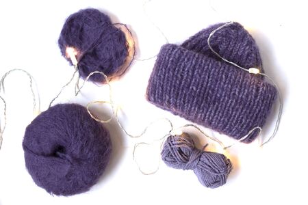 Knitted purple hat with garland on the white background. Woolen violet yarn balls. Top view. Flat layout.の写真素材