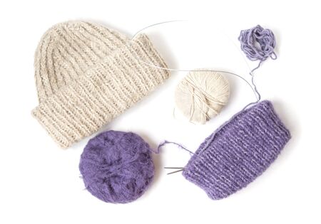 Beige knitted hat on the white background. Purple future hat. Colorful yarn balls. Top view. Flat lay. の写真素材