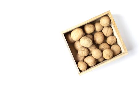 White background with walnuts in the wooden box. Copy space. Place for text and design. Top view. の写真素材