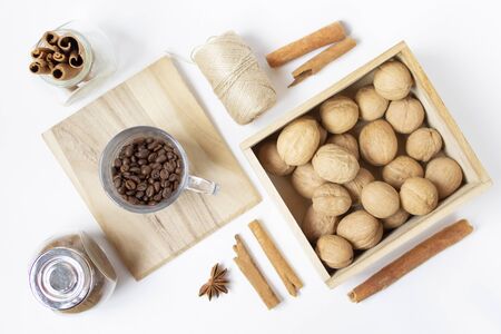 Coffee beans, walnuts in the wooden box, cinnamon, badian on the white background. Top view. Flat layの写真素材