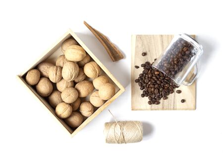 Beautiful layout with scattered coffee beans and walnuts in the wooden box on the white background. Top view. Flat layの写真素材