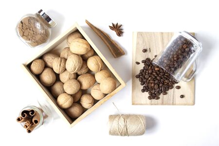 Beautiful layout with scattered coffee beans, walnuts in the wooden box, spices on the white...