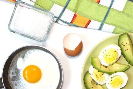 One fried egg on the little pan, avocado, boiled egg, dish towel. White background. Top view. Flat lay.の写真素材