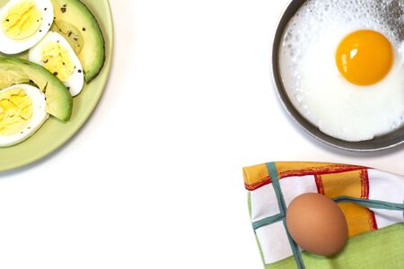 One fried egg on the little pan, avocado, boiled egg, dish towel. White background. Top view. Flat lay. Copy space. Place for text and designの写真素材
