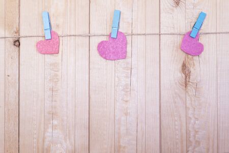 Felt hearts on the rope with clothespins. Wooden background. Cop space. Place for text and design.の写真素材