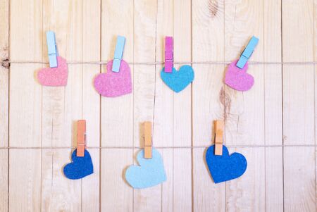 Colorful felt hearts on the rope with clothespins. Wooden background. Cop space. Place for text and design.の写真素材