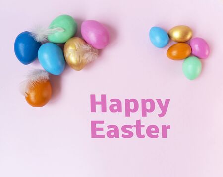 Golden, pink, blue, green, orange eggs on the light pink background. Top view. Flat lay. The pink...