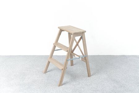 Wooden staircase and stool. A room in the photo studio. White wall. Grey floor. Copy space. Place...
