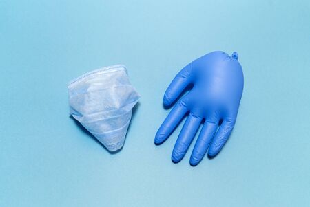 Medical glove and mask on the blue background. Flat layout. Minimal pandemic concept. Copy space. Place for text and design.の写真素材