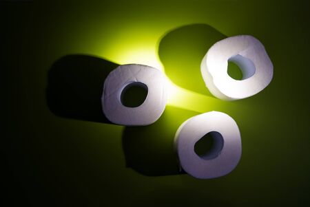Illuminated toilet paper on the neon green background. Minimalism idea. Scarce products in isolation...