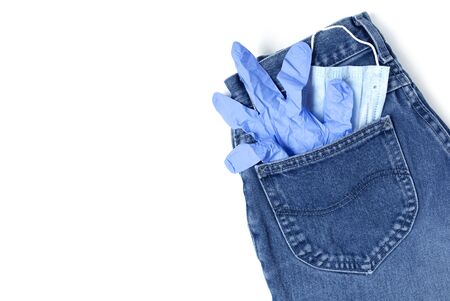 Classic blue jeans on the white background. Medical mask and gloves in the pocket. Pandemic concept. Copy space. Place for text and design. Top view. Flat layoutの写真素材