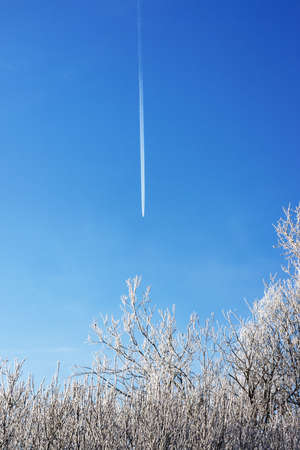Trail from an airplane in the sky on a cold sunny dayの写真素材
