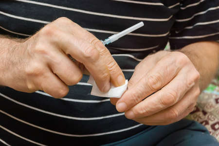 The man rubs with disinfectant wipe ampoule with medication to make himself a prickの写真素材