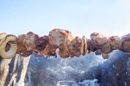 Appetizing slices of roast pork on the grill over coals on a picnicの写真素材