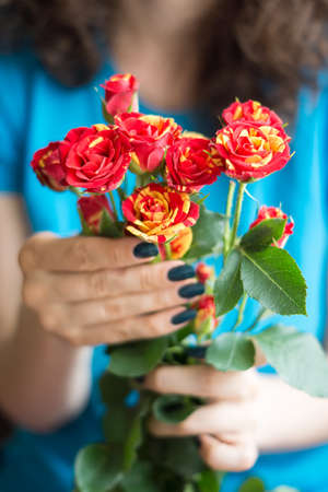 Bouquet red and yellow roses with stems in female handsの写真素材