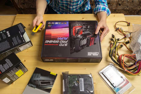 TVER, RUSSIA - NOVEMBER, 21, 2016: Woman unpacks using stationery knife components for the assembly of the computer at a wooden table.のeditorial素材