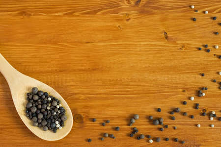 A mix of peppers and a wooden spoon laid out on a wooden table.の写真素材