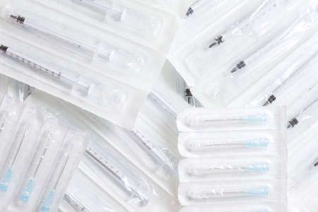 New syringes and needles lie on the surface, packed in sealed bags.の写真素材