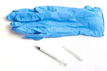 Gloves and an integral part of the syringe lying next to each other on a white background.の写真素材