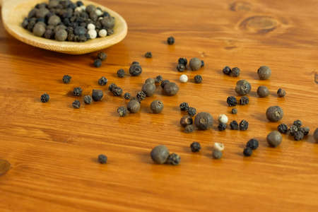 A mix of whole peppers lying in a wooden table background with wooden spoon, filled with the same mixture.の写真素材
