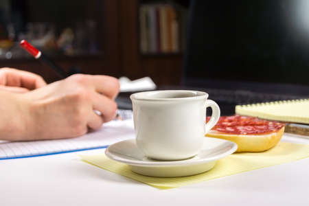 White Cup with coffee on background of the writing of man and sandwich.の写真素材