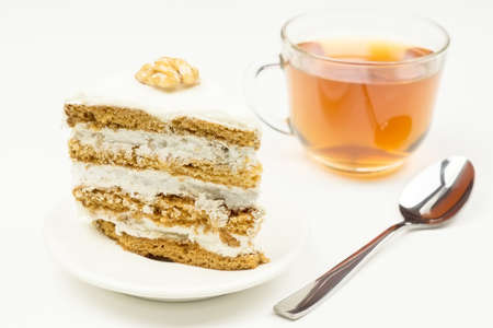 Piece of cake with cream, teaspoon, glass Cup with tea on white background.の写真素材