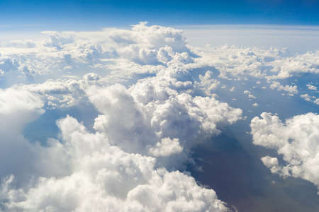 Blue clouds high above the ground, view from airplane window