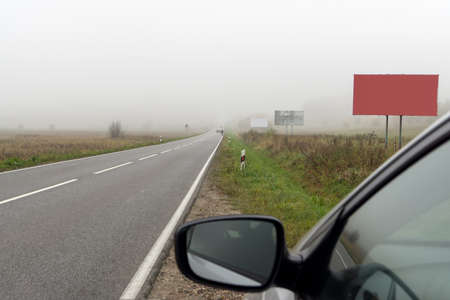 Road leaves in a field covered with a fog on an autumn morning