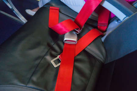 Red seat belt on the empty seat in the airplane