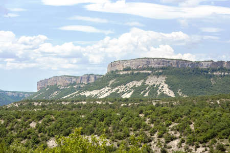 Low mountains surrounded by green bushes on a sunny summer day