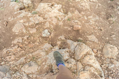 Foot in trekking sneakers on a rocky surfaceの写真素材