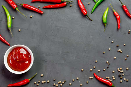 Green and red hot peppers and sauce on a concrete backgroundの写真素材
