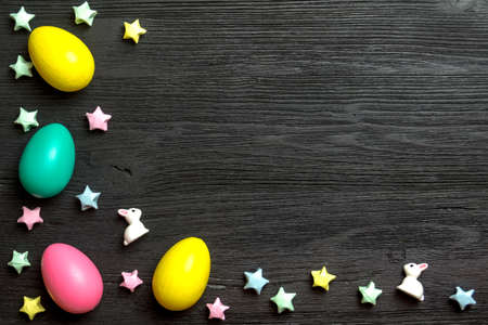 Easter background with bunnies, colorful stars and eggs on a wooden surfaceの写真素材