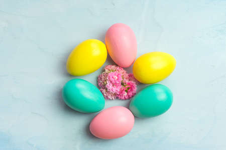 Multi-colored Easter eggs and pink Kalanchoe flowers on a blue backgroundの写真素材