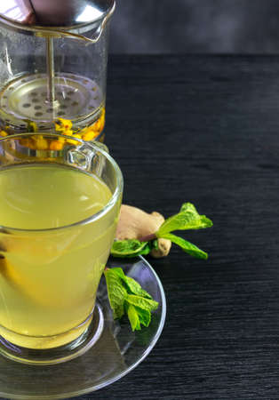 Mug and french press with aromatic sea buckthorn tea with mint, cinnamon and gingerの写真素材