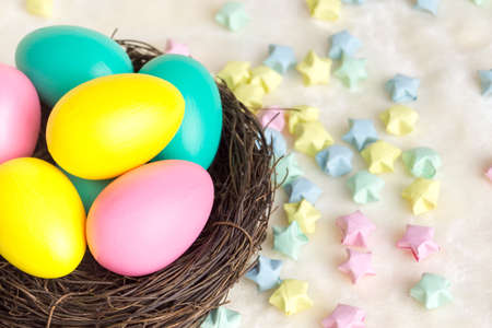 Multi-colored eggs in a nest of twigs and multi-colored stars. Easterの写真素材