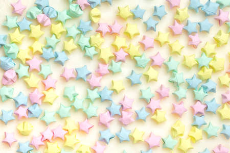 Beautiful background with light multi-colored paper stars on a beige plaid