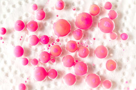 Drops of pink paint in oil on a white backgroundの写真素材