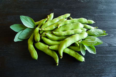 Ripe bean pods on a black wooden table. Agricultural concept, harvest seasonの写真素材