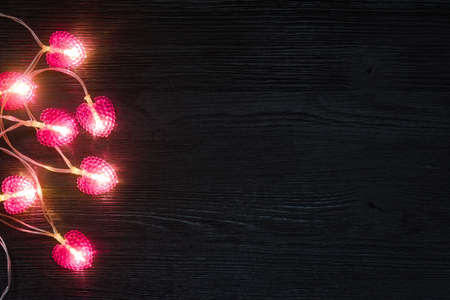 Black wooden background with a pink garland in the shape of hearts. Valentines day backdropの写真素材
