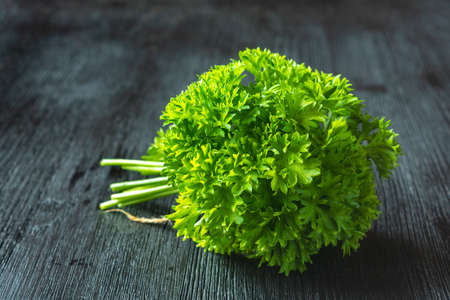 A bunch of fresh curly parsley on a wooden table. Garden vitamins, farm harvest season, spicy herbsの写真素材